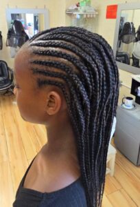 A black kid with cornrows extending into single braids at Tete Hazel